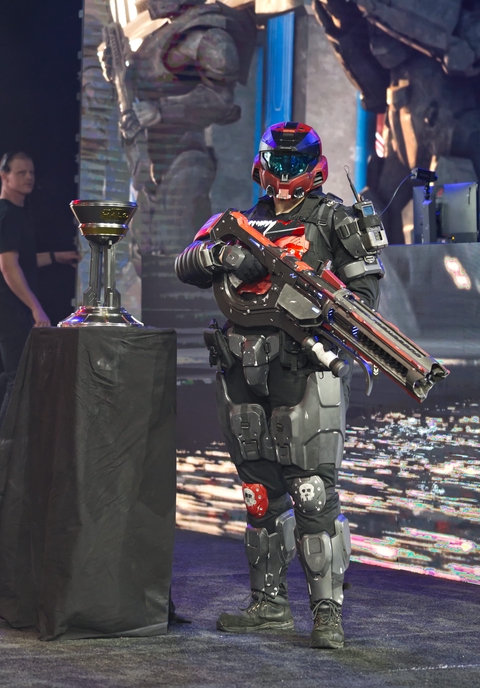 Spartan with a Shock Rifle next to the Halo World Championship trophy.